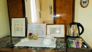 A reception desk with a framed menu, a coffee pot, and a set of keys. - Villa Liberty B&B (Fano)
