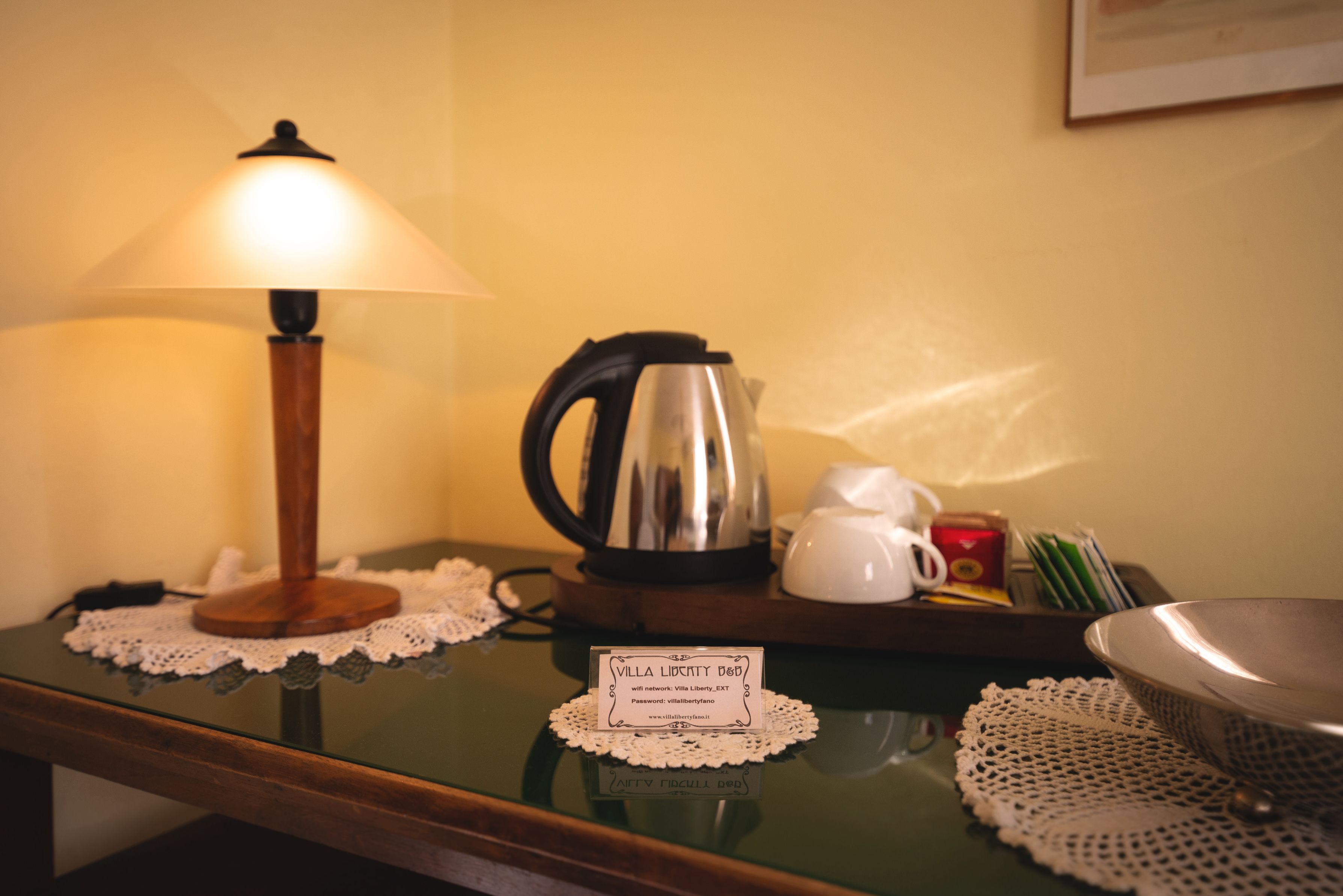 Una mesa con una lámpara, un hervidor, una tetera y un cartel con texto.