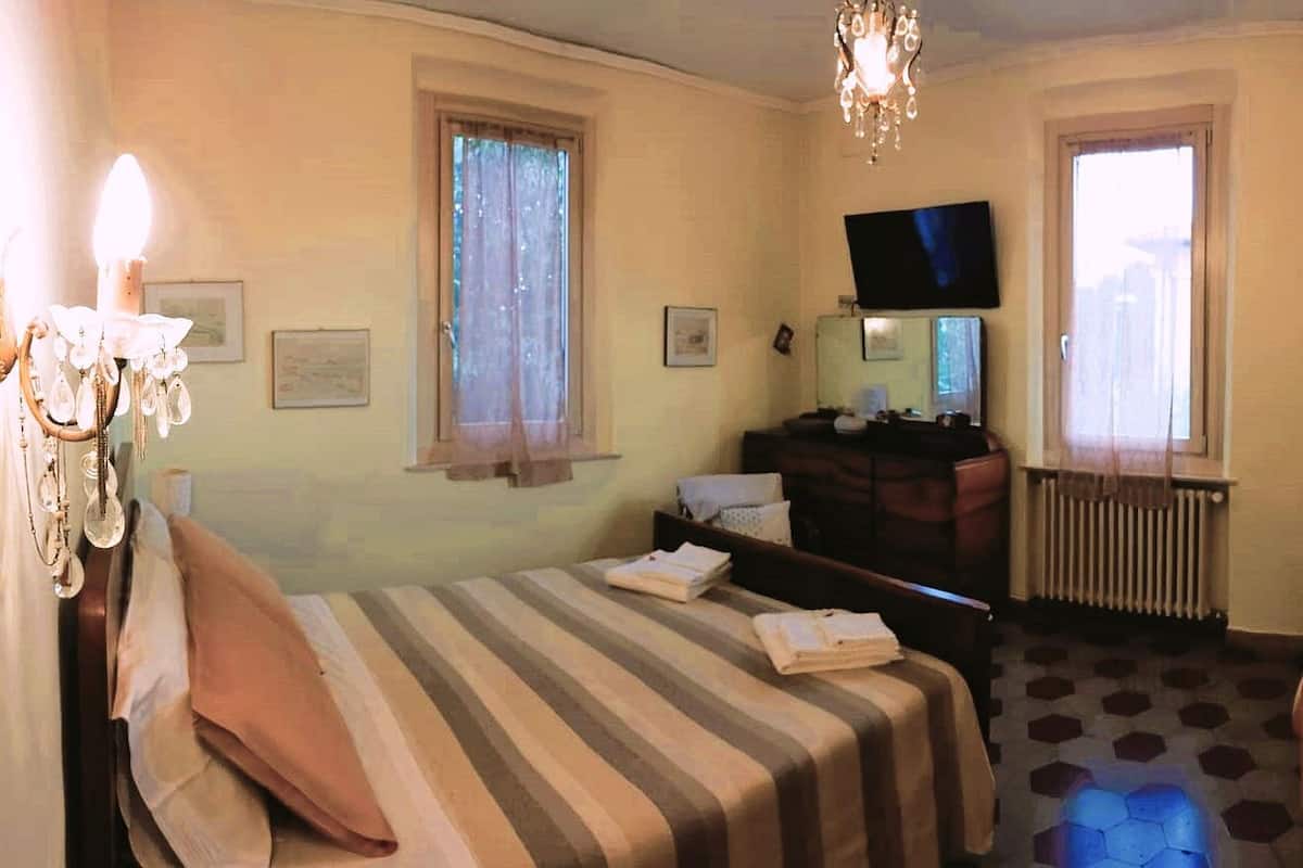 A hotel room with a bed, a sofa, a TV, a dresser, and a chair.