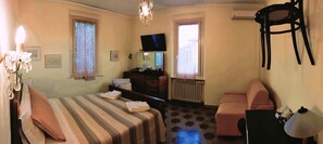 A hotel room with a bed, a sofa, a TV, a dresser, and a chair.