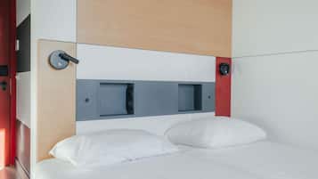 Een moderne hotelkamer met een bed, een bedieningspaneel en een klein plankje.