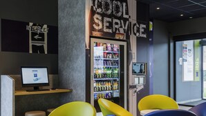 Un intérieur moderne avec une enseigne indiquant « Service rapide et efficace », un distributeur automatique et des chaises colorées.