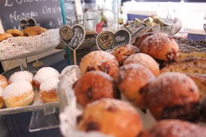 A display of various pastries and baked goods, including doughnuts and cookies, arranged on trays and stands.