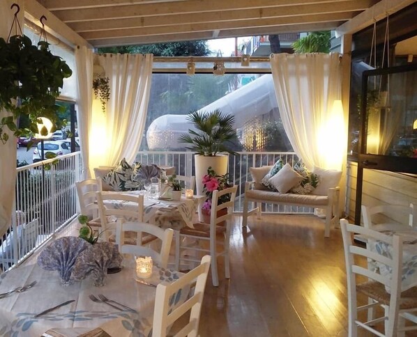 A cozy outdoor dining area with white furniture, potted plants, and a view of a slide in the background.