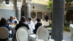 A dining area with white chairs and tables, surrounded by intricately patterned walls and columns.