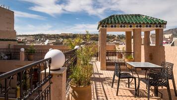 A rooftop terrace with a pergola, outdoor seating, and a potted plant.