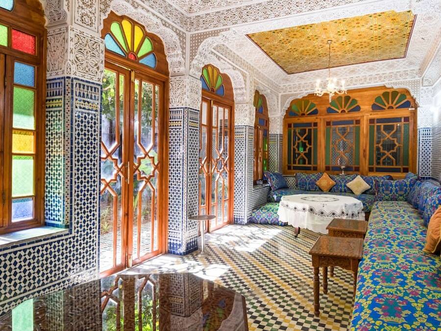 Una habitación con elaborados trabajos en azulejos, piso estampado y un sofá grande y colorido.