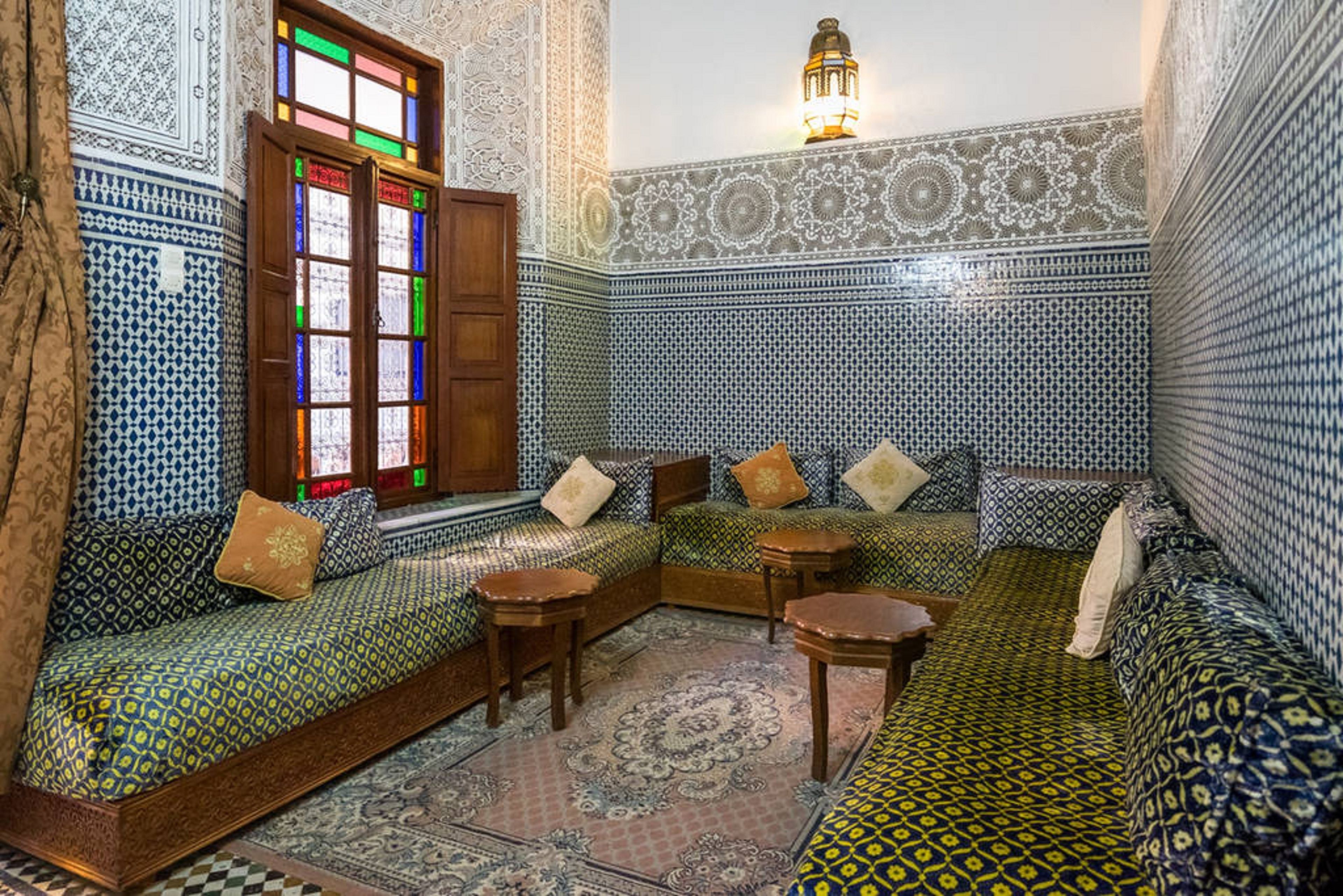 A traditional Moroccan riad with a central seating area, ornate tile walls, and a decorative lantern.