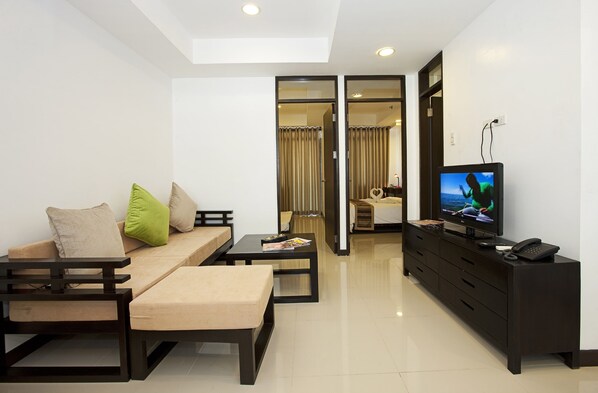 A modern living room with a sofa, coffee table, TV, and a dining area. - Copenhagen Main Residences (Mandaue)