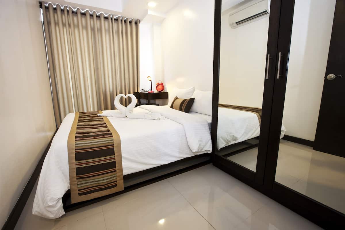 A hotel room with a bed, a nightstand, a lamp, and a mirror.