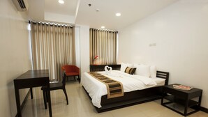 A hotel room with a bed, a desk, a chair, and a nightstand. - Copenhagen Main Residences (Mandaue)