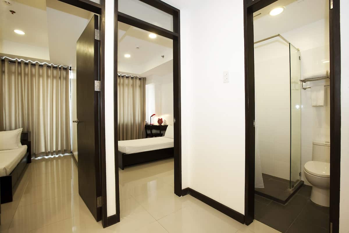 A hotel room with a bed, a bedside table, a mirror, a shower area, and a toilet.