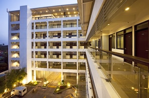 A multi-story hotel with a modern design, featuring a central courtyard with plants and a parking area. - Copenhagen Main Residences (Mandaue)