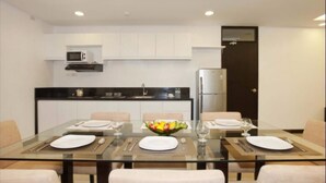 A modern kitchen with white cabinets, a microwave, and a refrigerator. - Copenhagen Main Residences (Mandaue)