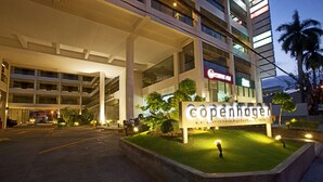 A hotel entrance with a sign reading "Copenhagen" and a well-lit outdoor area with a grassy platform and a few trees. - Copenhagen Main Residences (Mandaue)
