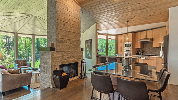 A spacious living area with a fireplace, a dining table with chairs, and a kitchen with wooden cabinets and modern appliances.