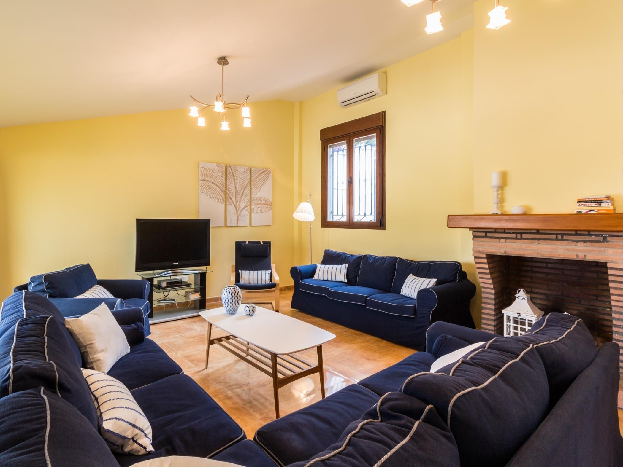 A living room with a TV, two sofas, a coffee table, and a fireplace.