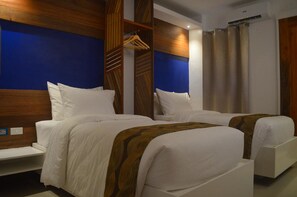 A hotel room with two beds, a wooden headboard, a wardrobe, and a shower curtain.