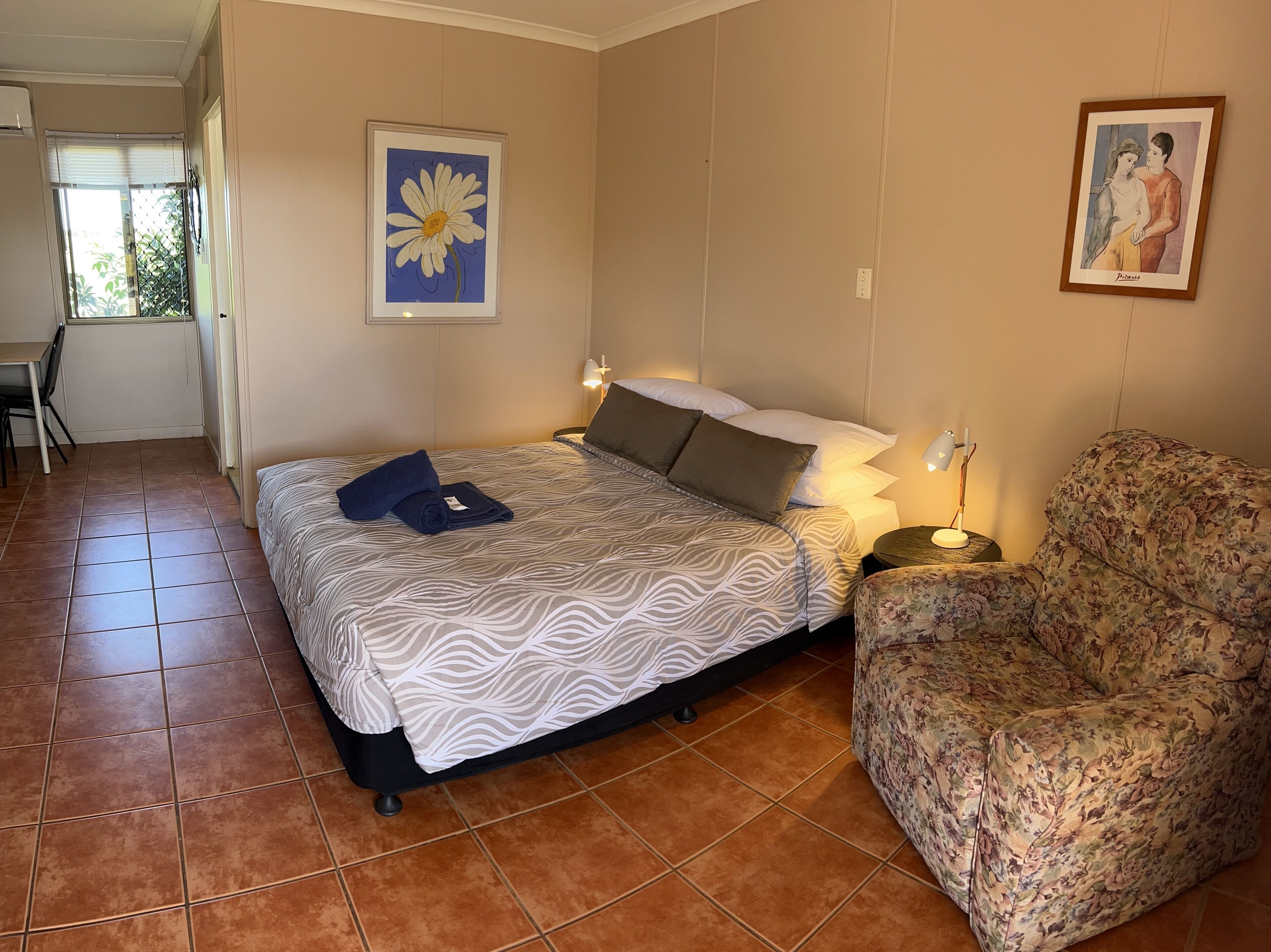 Una habitación de hotel con cama, una silla, un escritorio y una ventana.