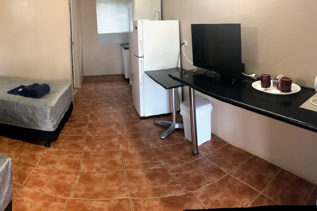 Una habitación de hotel compacta con dos camas individuales, un escritorio pequeño con televisor y una silla.