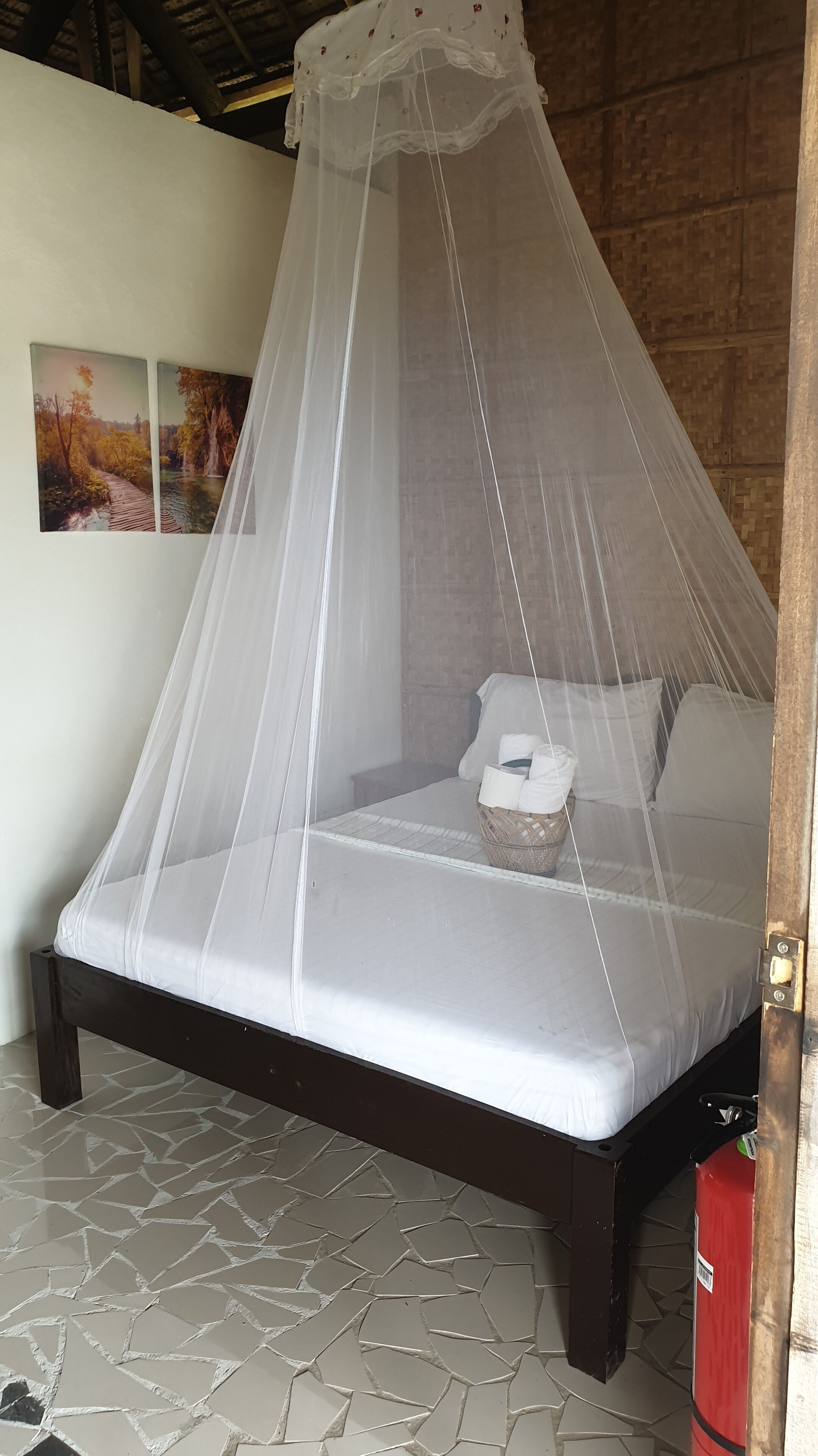A bed with a white canopy, a small bedside table, and a basket.
