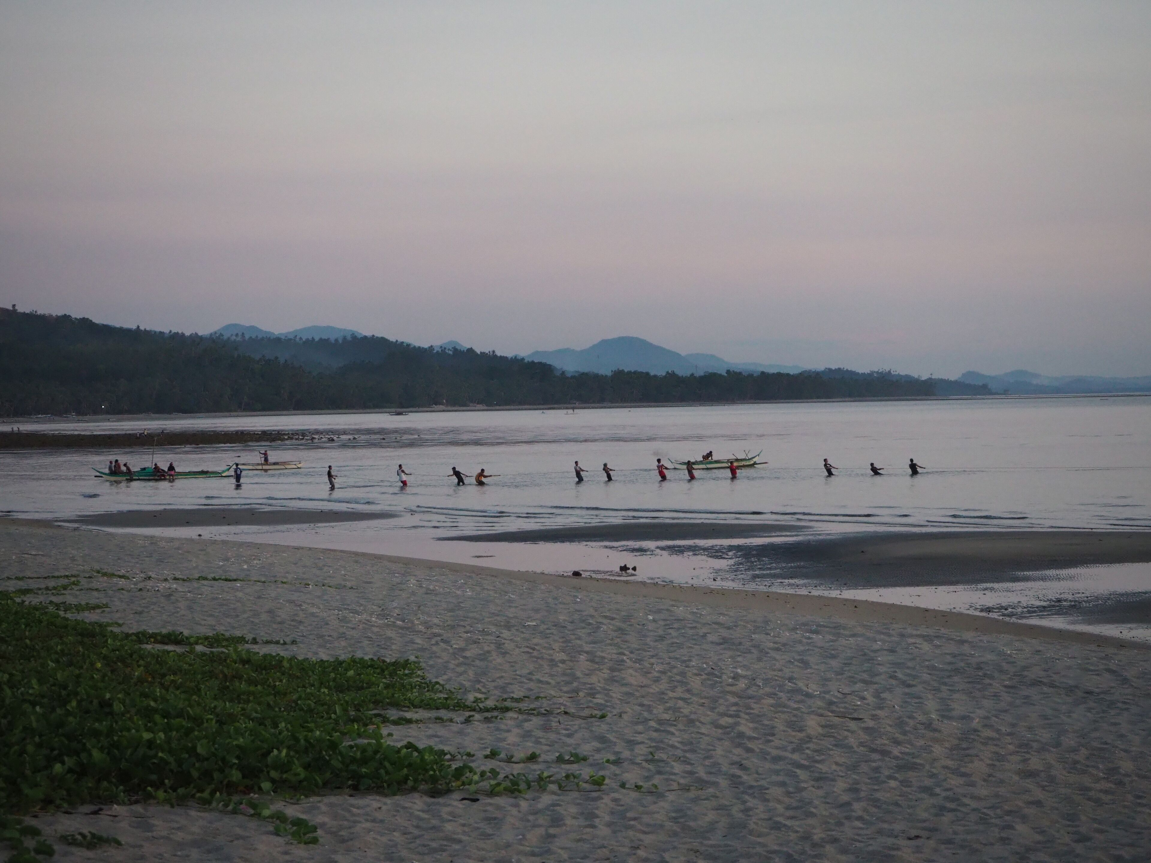Una playa con barcos y gente en el agua.