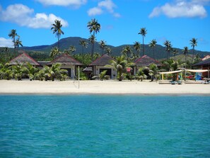 A beach resort with thatched-roof huts, palm trees, and a clear view of the ocean. - Footprints Beach Resort (San Andres)