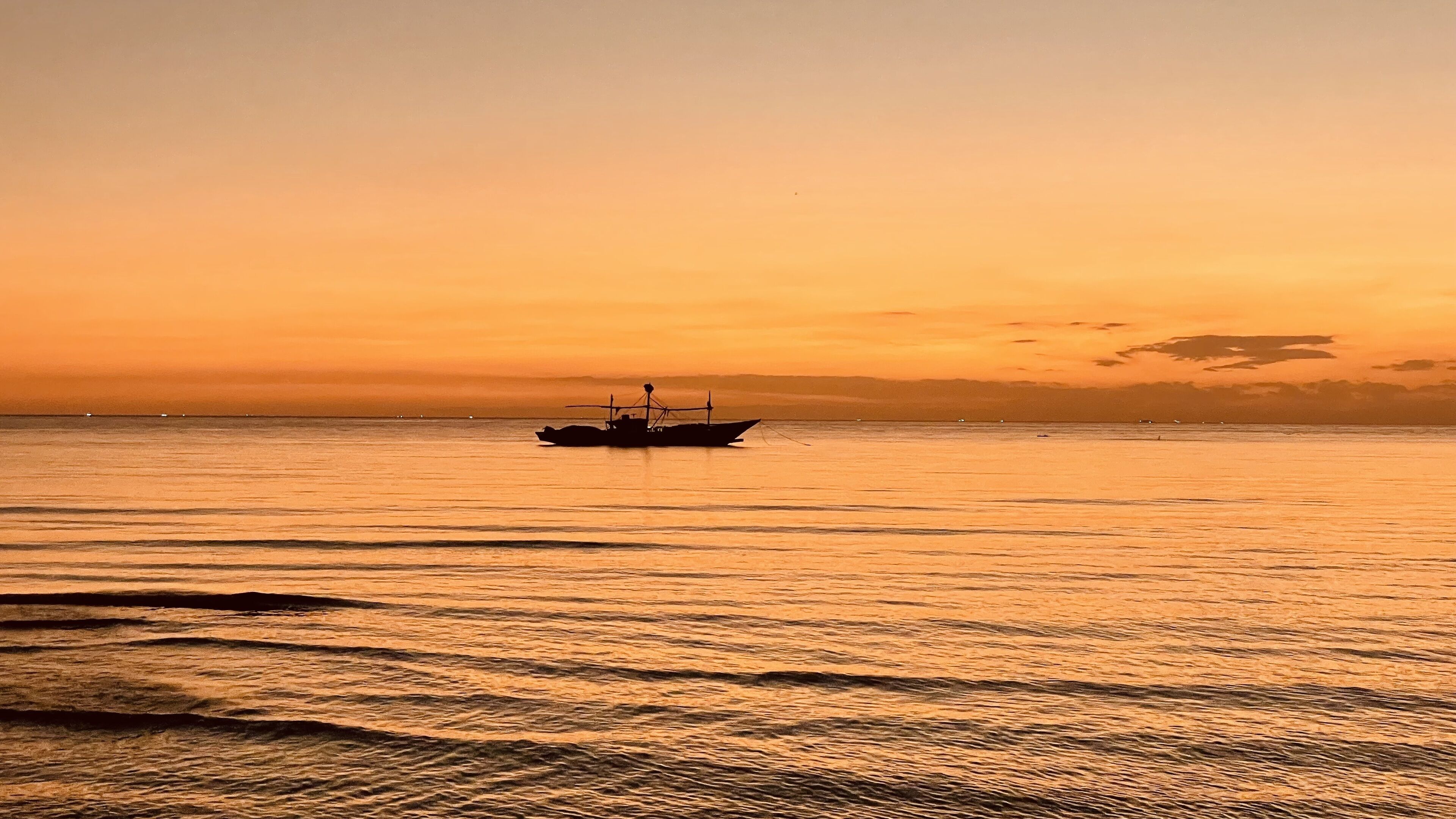Un bateau sur une eau calme, au coucher du soleil.