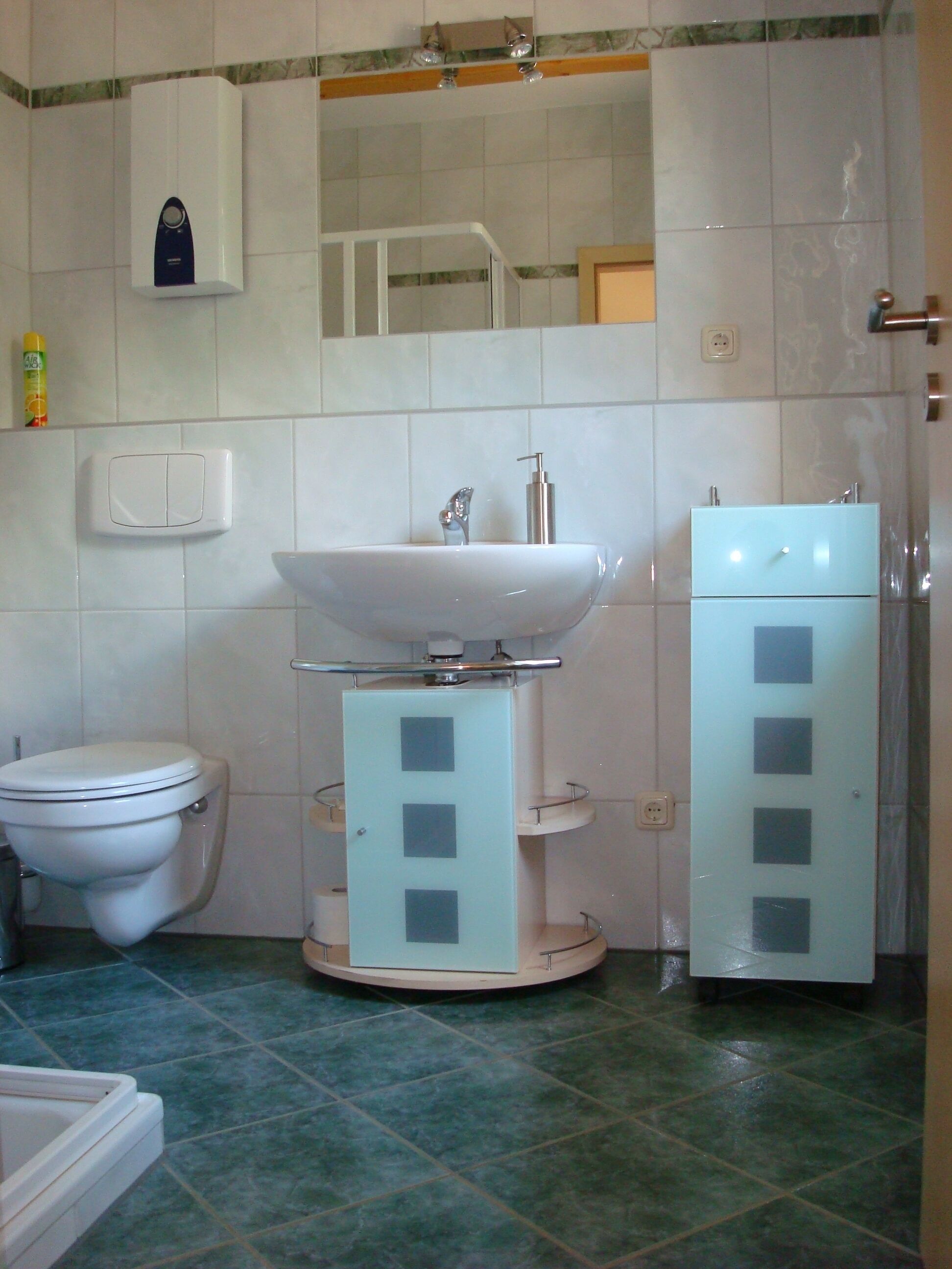 A bathroom with a toilet, sink, and cabinet.
