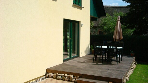 Une terrasse avec des meubles d’extérieur et une bordure en pierre.