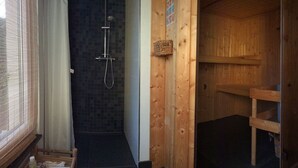 Un intérieur en bois avec une douche, une porte en bois et une chaise à rayures.