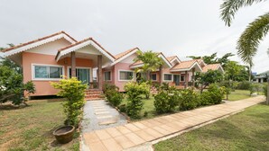A row of pink villas with tiled roofs, a paved walkway, and a well-maintained garden. - OYO 949 Sansuk Resort Paknampran (Pranburi)