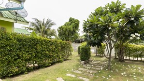 A garden with a pathway, green hedges, and trees. - OYO 949 Sansuk Resort Paknampran (Pranburi)