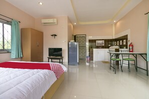 A hotel room with a bed, a desk, a chair, a refrigerator, and a kitchen area. - OYO 949 Sansuk Resort Paknampran (Pranburi)