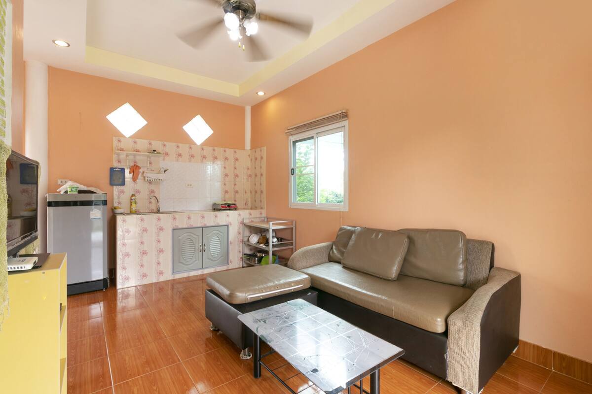 A compact living space with a kitchenette, a sofa, and a small table.