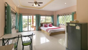 A hotel room with a bed, a dining table with chairs, a ceiling fan, and a refrigerator. - OYO 949 Sansuk Resort Paknampran (Pranburi)