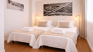 A hotel room with two beds, a large abstract painting, a wall-mounted sign, and two floor lamps.