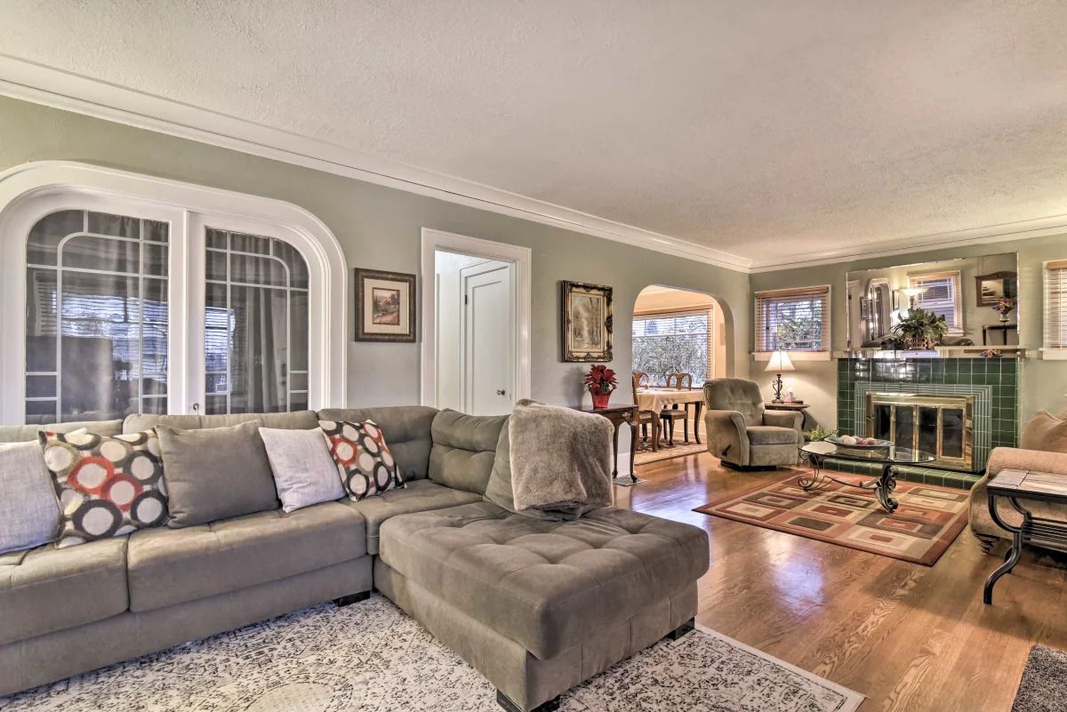 A living room with a sectional sofa, a fireplace, and a dining area in the background.