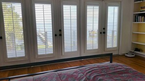 A bedroom with a bed, a bookshelf, and a window with blinds. - Romantic Escape; Open Gulf View; Your Own Private Dock!  Elevator to master. (Crystal Beach)