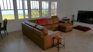 A living room with a brown sectional sofa, a small table, and a fireplace. - Romantic Escape; Open Gulf View; Your Own Private Dock!  Elevator to master. (Crystal Beach)
