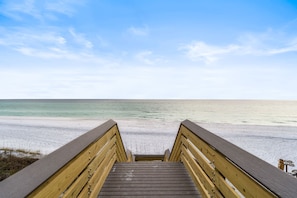 A wooden boardwalk leading to a beach with clear skies.