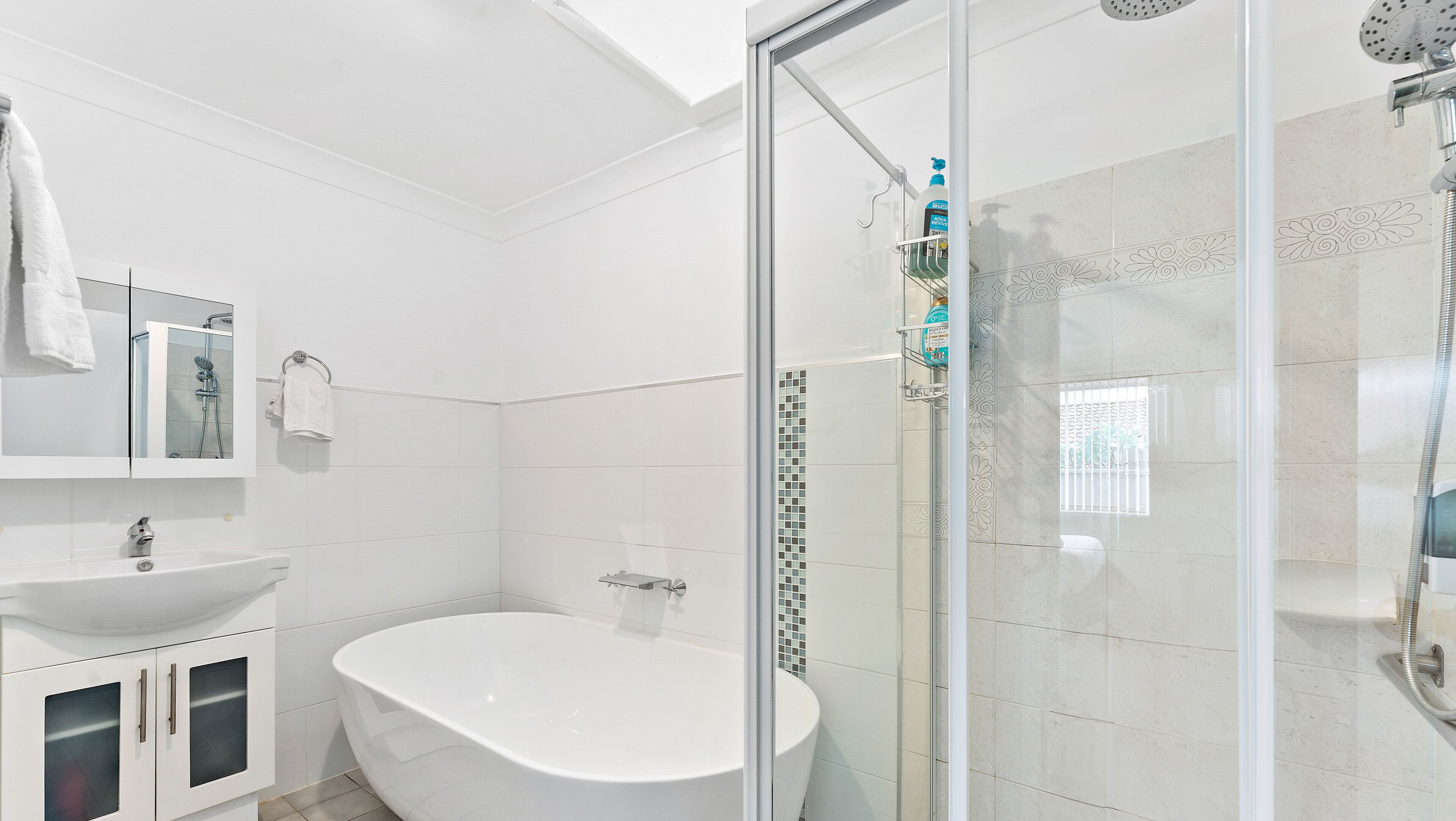 A modern bathroom with a freestanding bathtub, a glass-enclosed shower, and a white vanity with a sink.