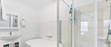 A modern bathroom with a freestanding bathtub, a glass-enclosed shower, and a white vanity with a sink.