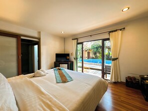 Una habitación de hotel con una cama grande, televisión y vistas a una piscina.