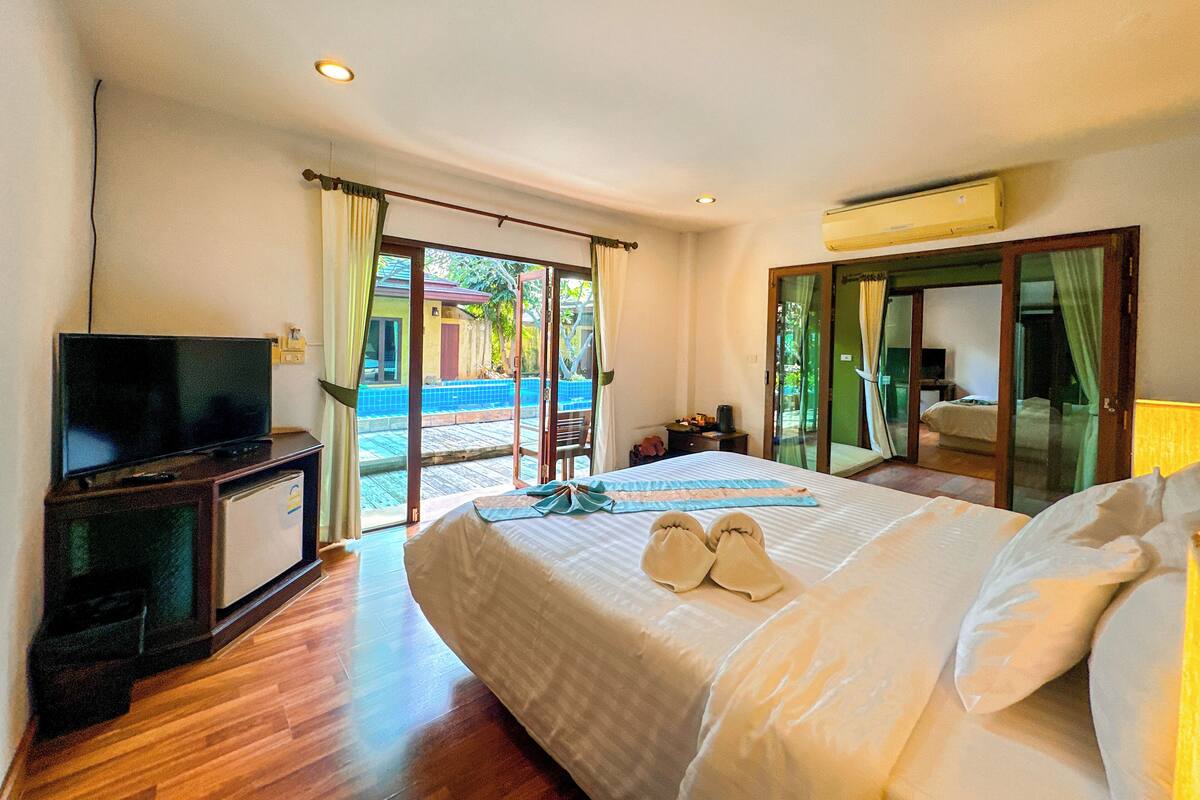 A hotel room with a bed, a TV, and a view of a swimming pool.