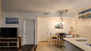 A compact kitchen with a dining area, a television, and a painting on the wall.