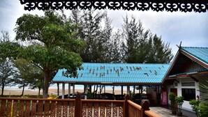 A wooden deck with a blue-roofed structure, surrounded by trees and a beach view. - Little Home Beach (Kui Buri)