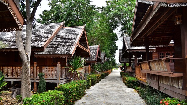 A pathway flanked by traditional wooden buildings with ornate railings and a well-maintained garden. - Little Home Beach (Kui Buri)