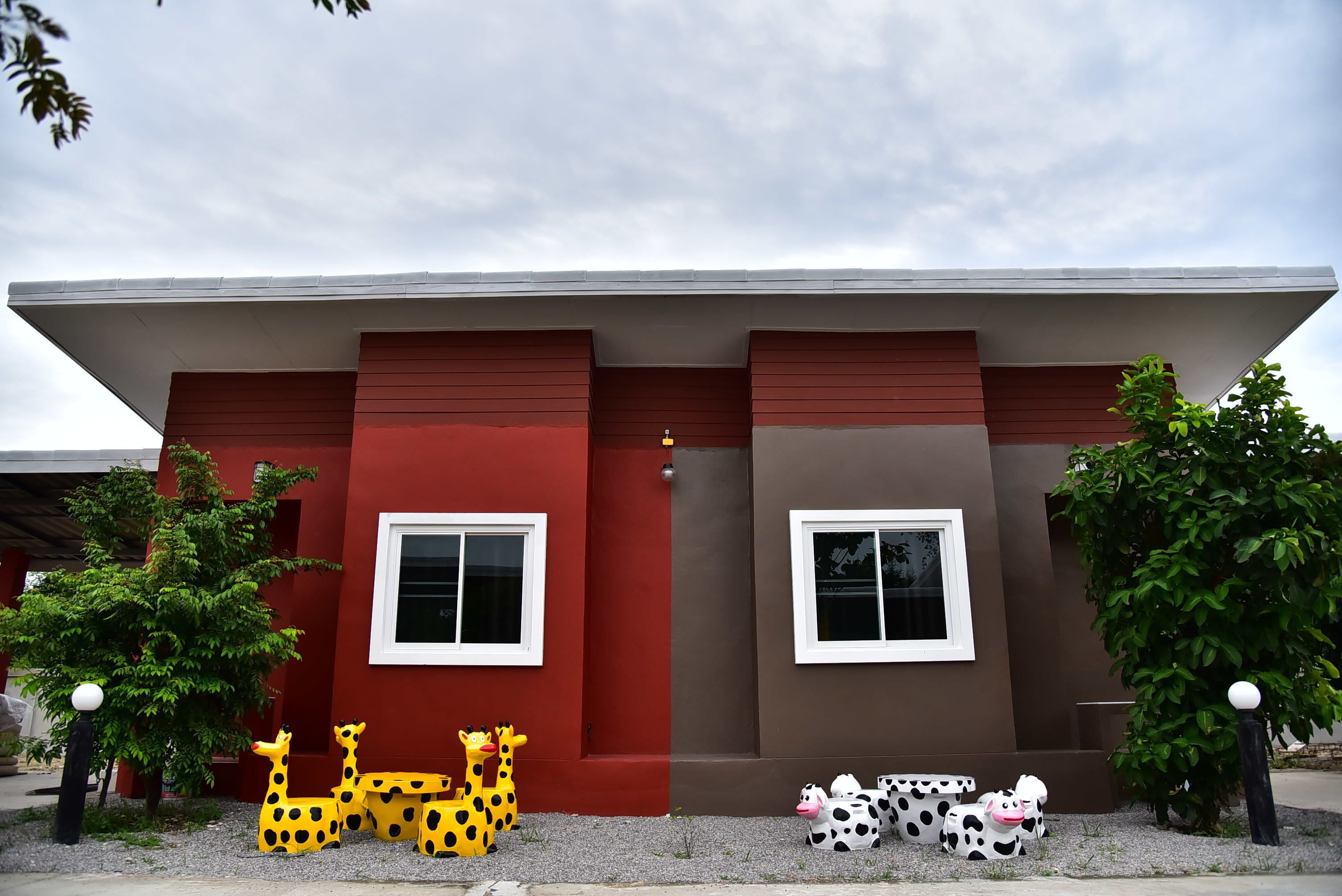 A modern building with two windows and a red and brown facade.