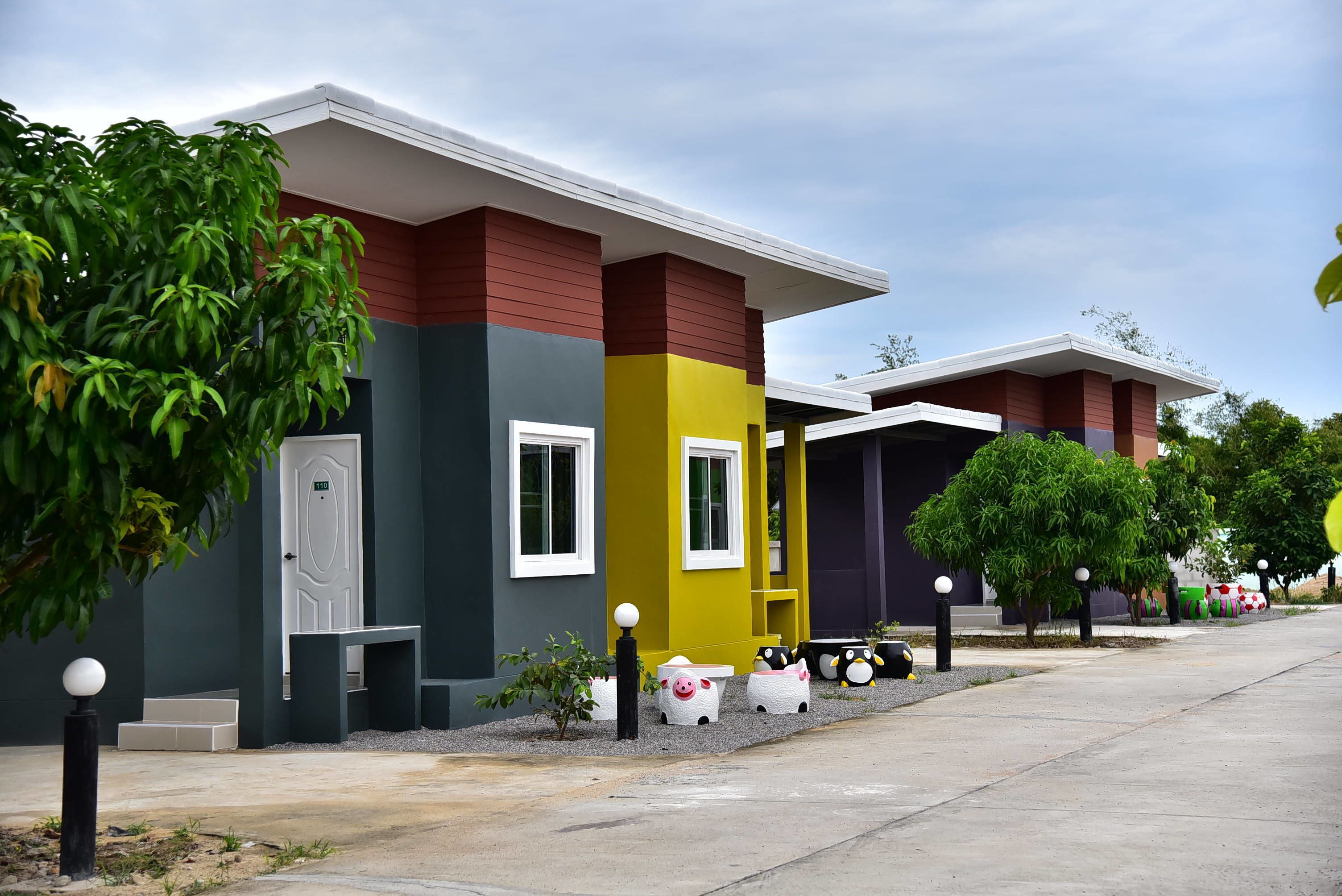 A modern building with a red, yellow, and grey facade, a white door, and a bench outside.